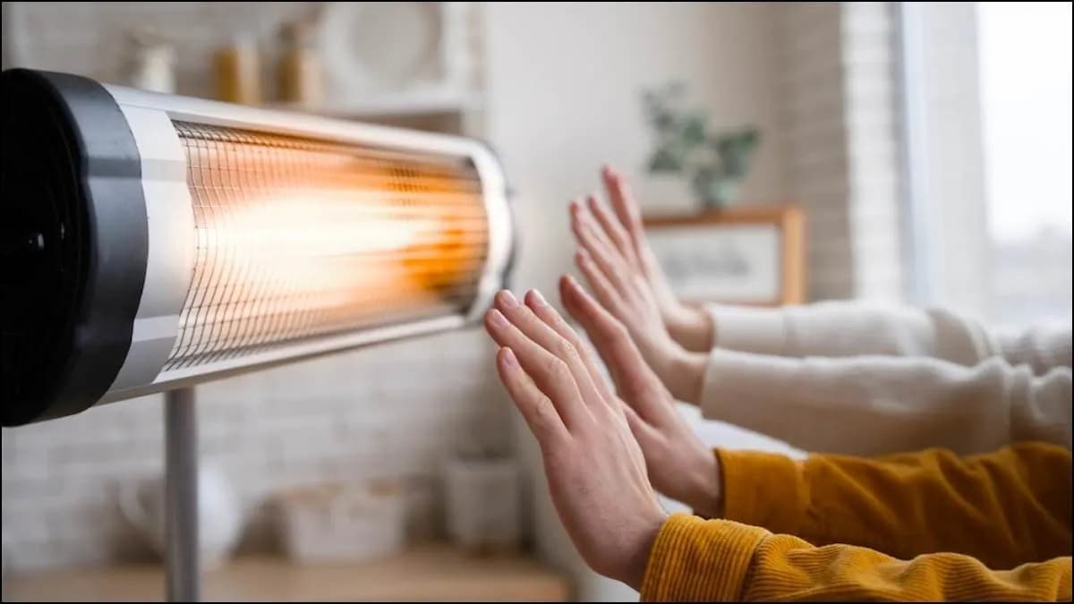 Händer som värms framför en värmelampa i ett mysigt hem