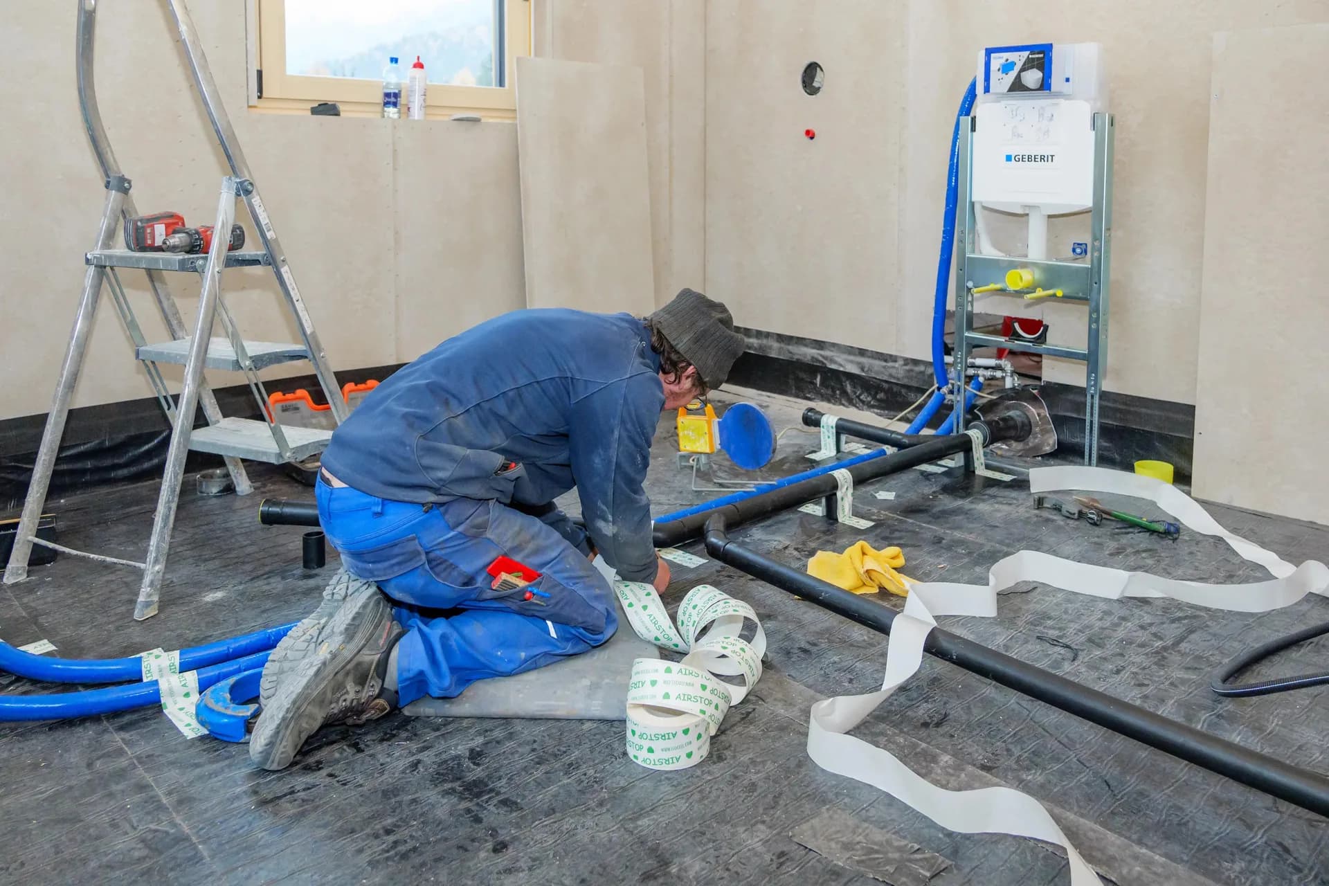 Rörmokare drar nya vattenledningar i golvet under en renovering