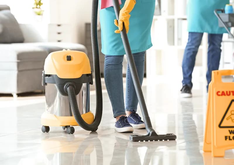 Städpersonal moppar och dammsuger golvet i ett kontor